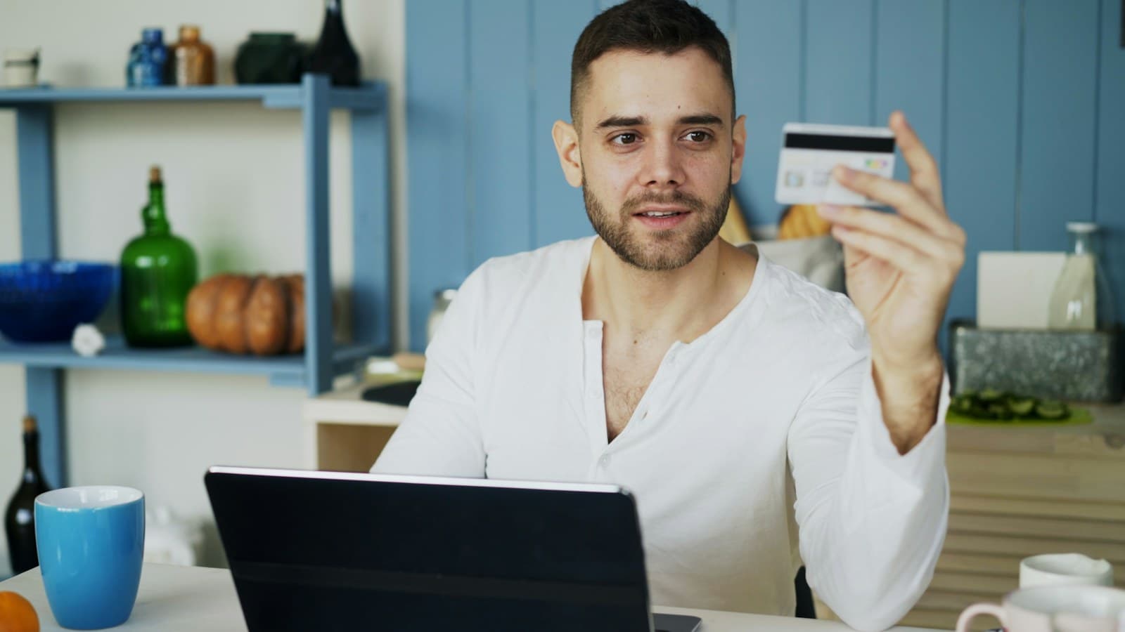 Customer holding a payment card while shopping online with a laptop